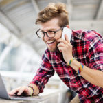 Man at a laptop and on the phone, who is happy to have found the editor he needs online.